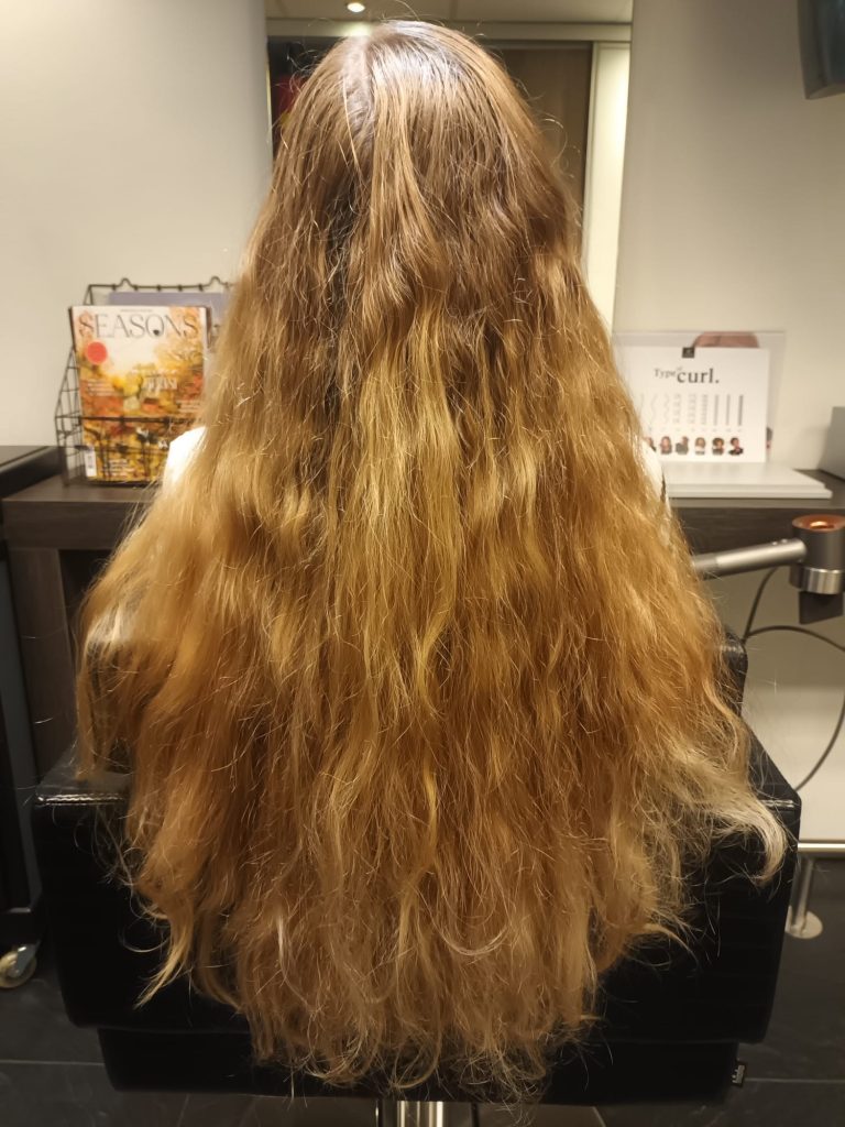 Lang blond golvend haar na behandeling bij Kapsalon Trendline